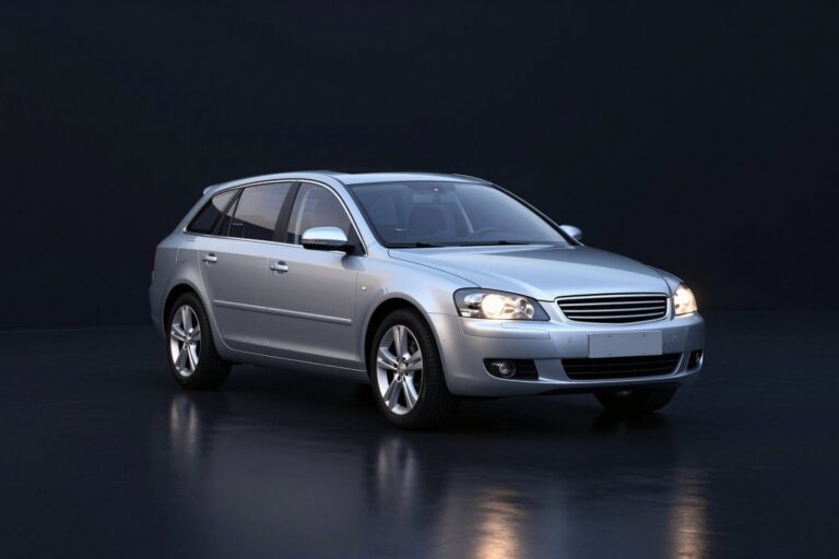 Silver estate car with long side windows, in a dark showroom