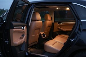 Tan leather seats and door panels, seen through the open rear door of the black saloon