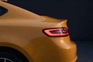 The slim red tail light set into the curved amber flank of the coupé