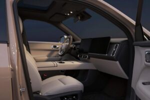 Warm grey fabric front seats, a two-tone dashboard and a large central display, seen through the open door