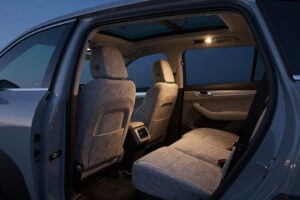 Grey wool rear seats and a panoramic glass roof, seen through the open rear door of the SUV