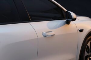 A flush door handle and the side mirror on the glacier white door of the electric saloon