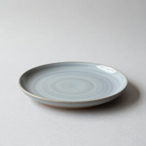 Round stoneware dinner plate in a soft blue-grey glaze with a bare clay foot