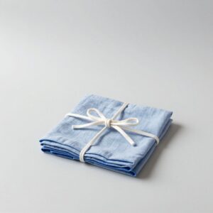 Four folded linen napkins in two tones of blue, tied with cotton string