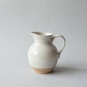 Small cream stoneware jug with a pinched spout and a loop handle