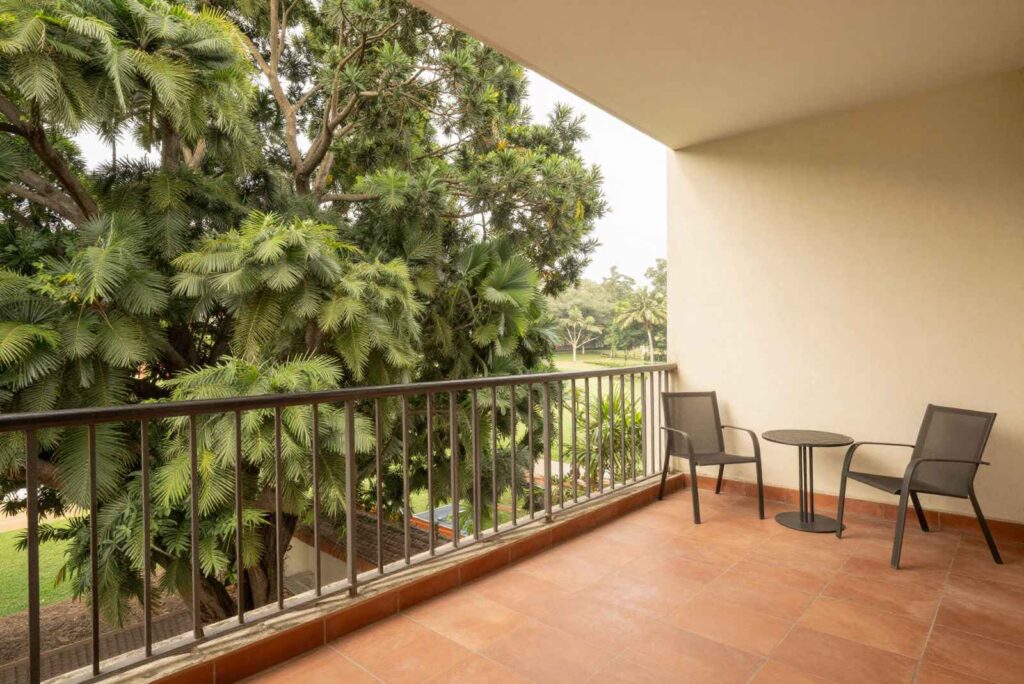 Covered balcony with two chairs looking out over tall trees